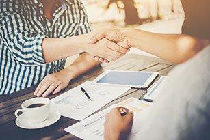 Two people shaking hands across a table